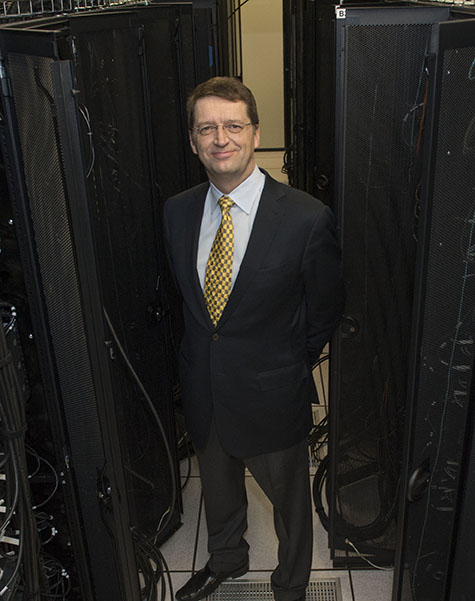 Tuomas Sandholm poses between banks of supercomputers.