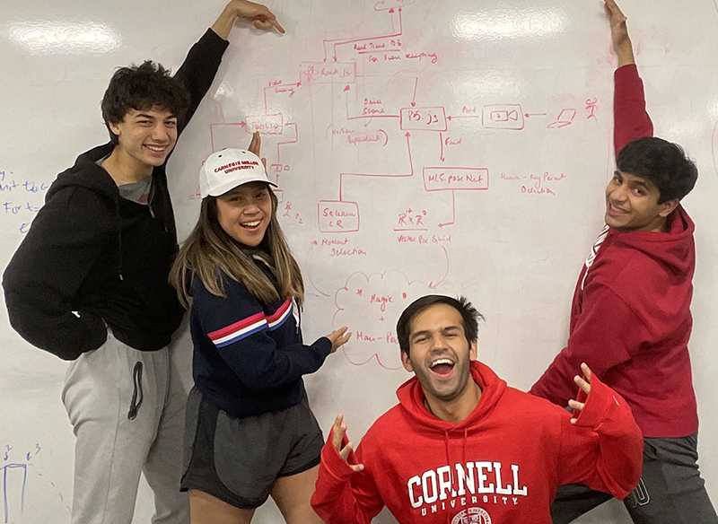Alex Li, Athiya Deviyani, Ranadeep Singh and Abuzar Khan pose in front of a dry erase board that shows the brainstorming they did to create their app, TwerkOut.
